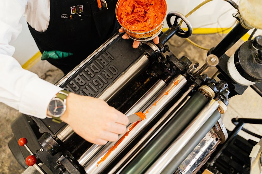 Printing press operator working with ink rollers